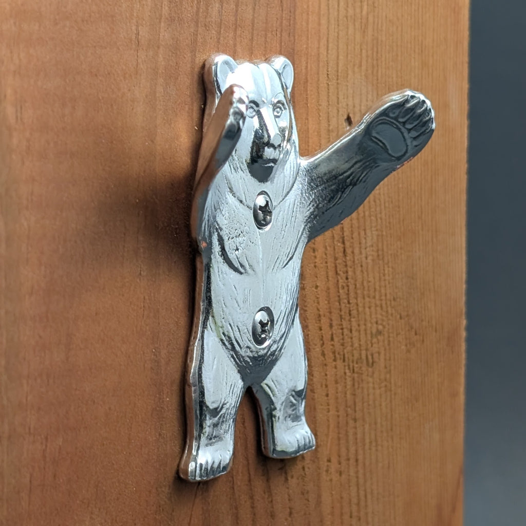 Pewter bear wall hook mounted on a wood board, close-up with arm raised to hold items