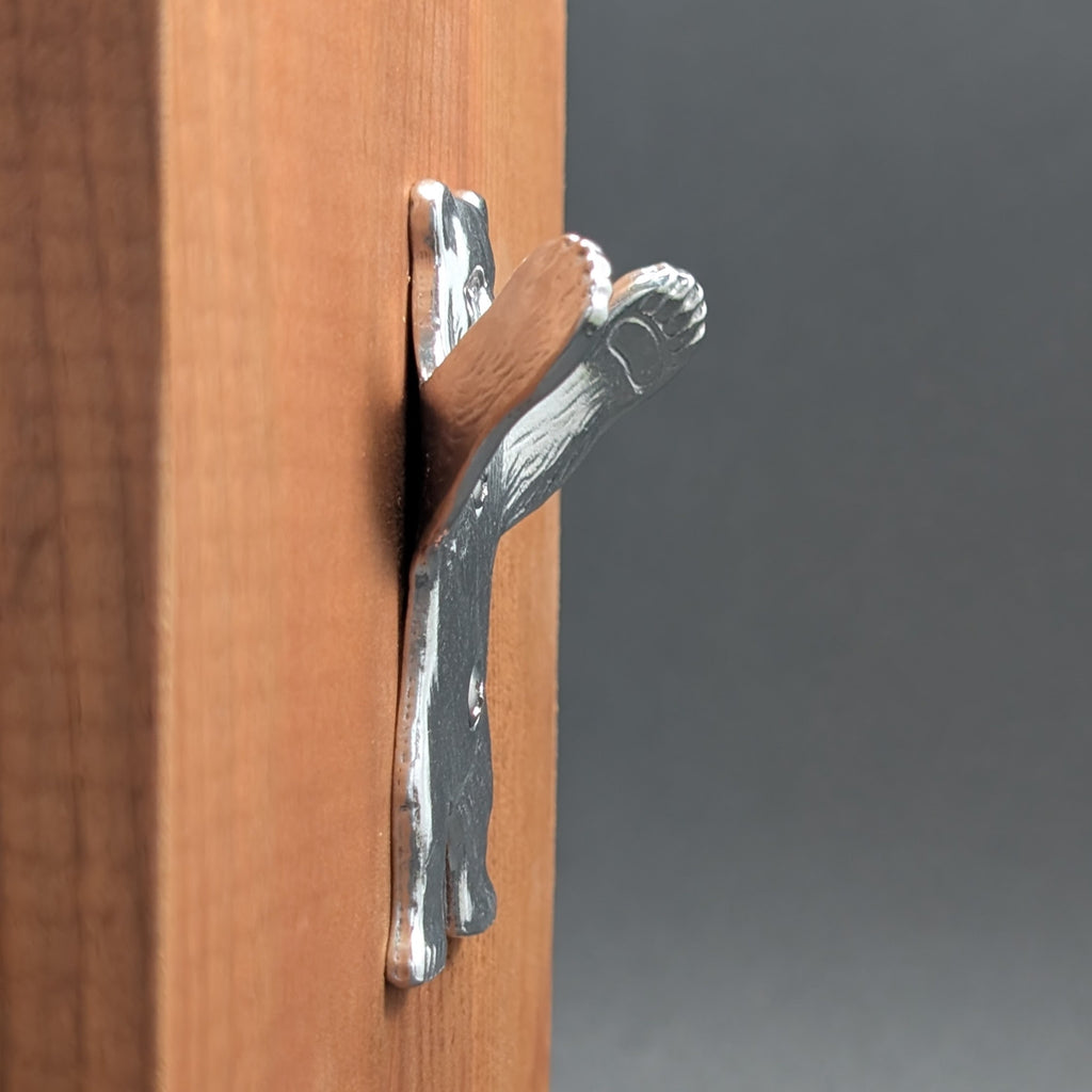 Close-up of a pewter bear wall hook paw mounted on wood