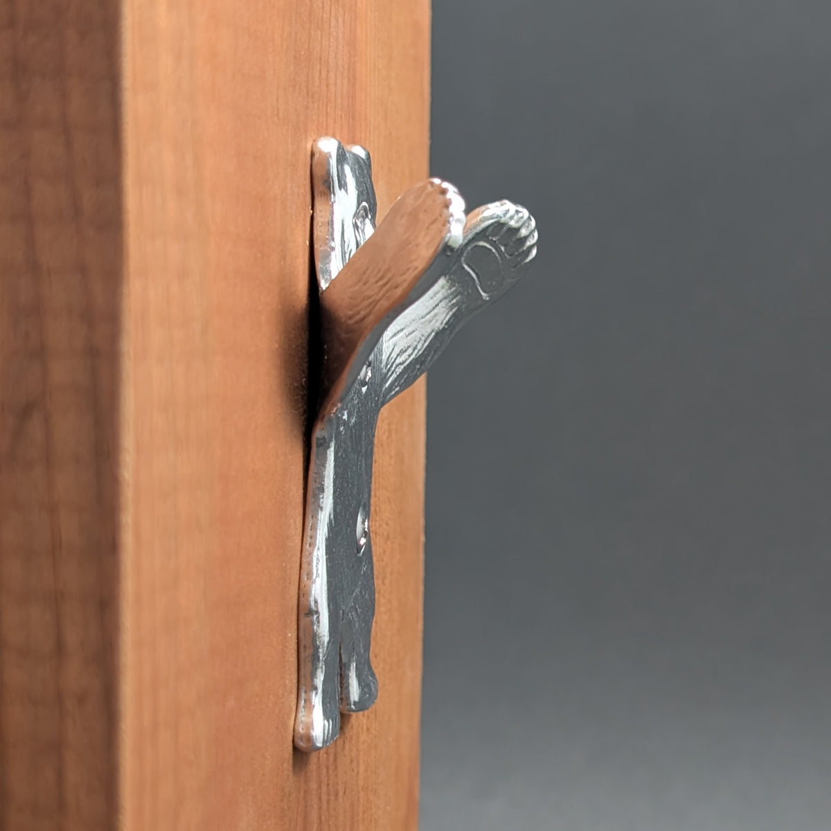 Close-up of a pewter bear wall hook paw mounted on wood