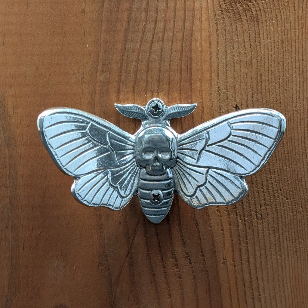 Pewter death's head hawkmoth wall hook mounted on a wood board, front view