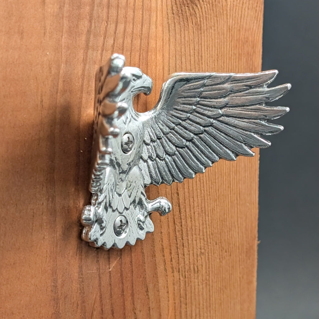 Pewter eagle wall hook mounted on a wood board, angled close-up