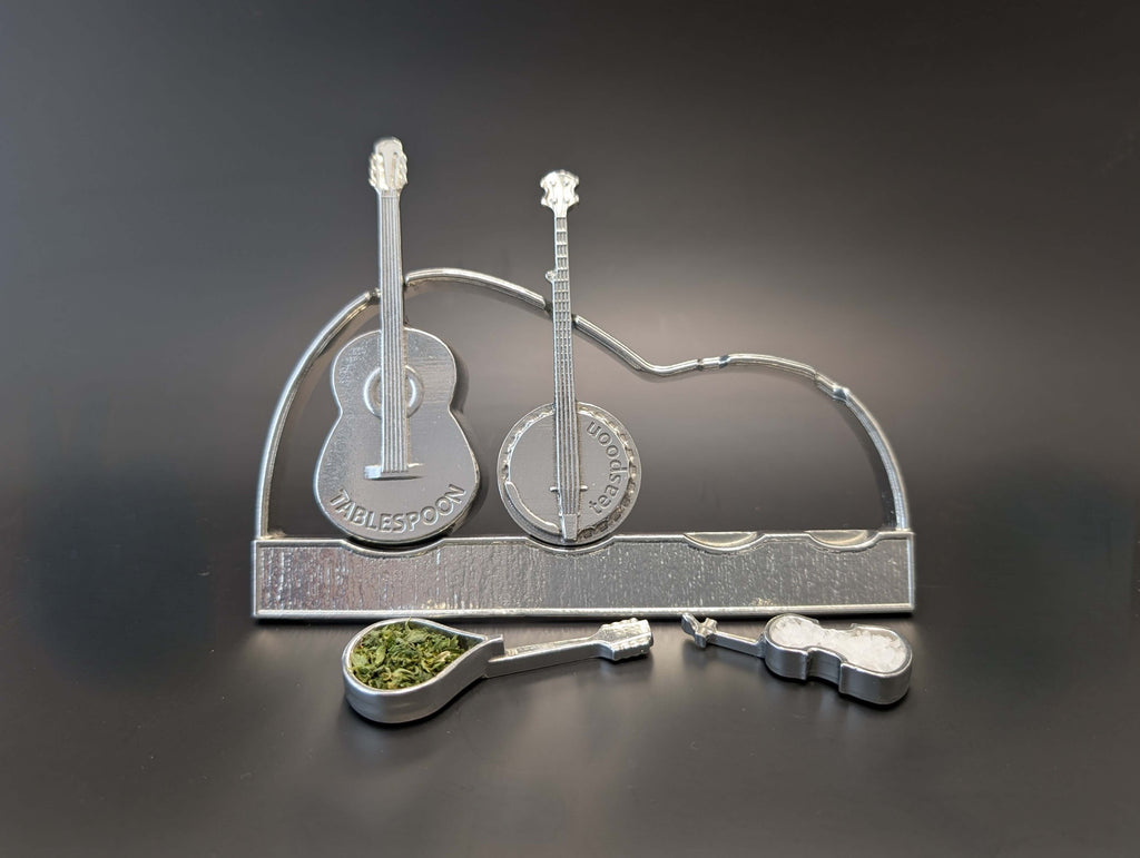 Pewter instrument guitar spoons on display stand. Guitar, banjo, mandolin, fiddle. Black background