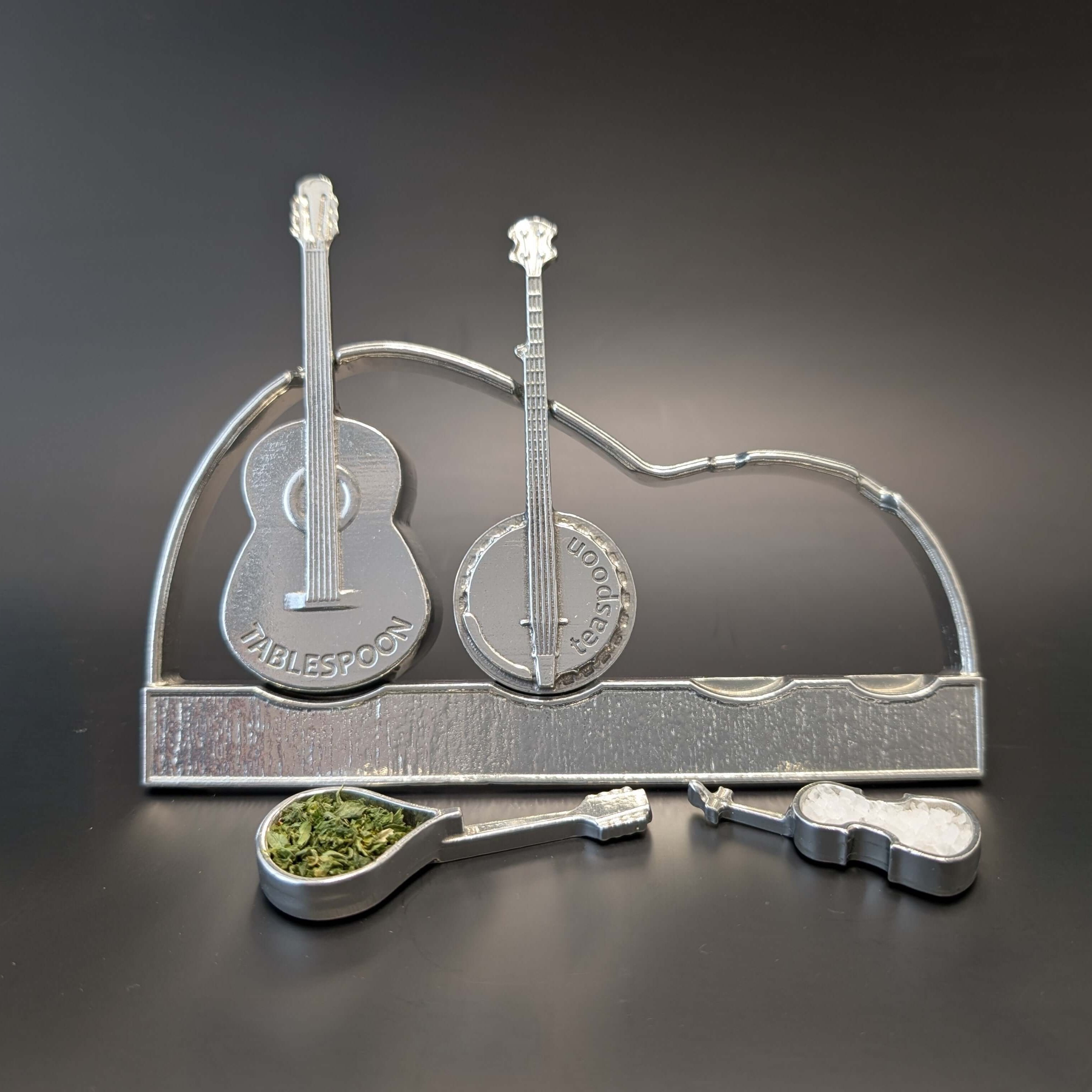 Pewter instrument guitar spoons on display stand. Guitar, banjo, mandolin, fiddle. Black background