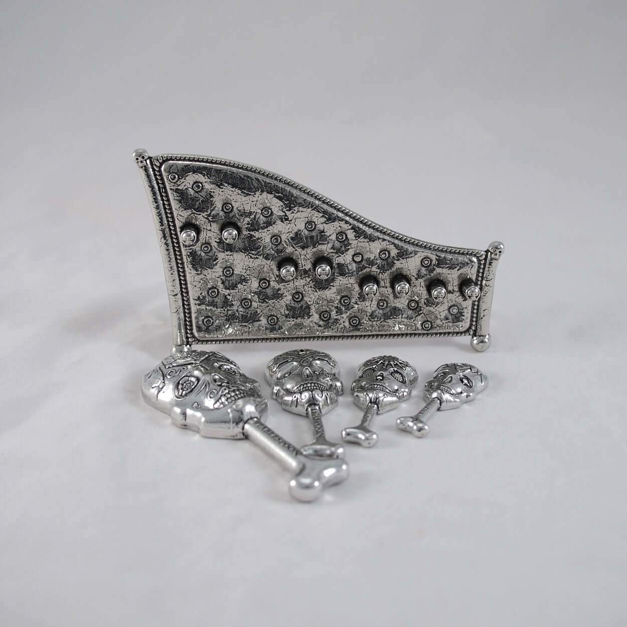 Pewter skull measuring spoons on display stand. white background